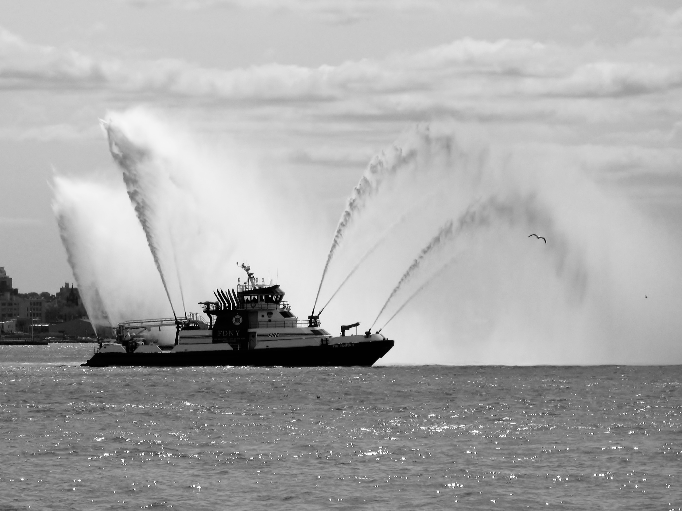 Un bateau-pompe du FDNY projetant de grandes gerbes d’eau dans la baie de New York
